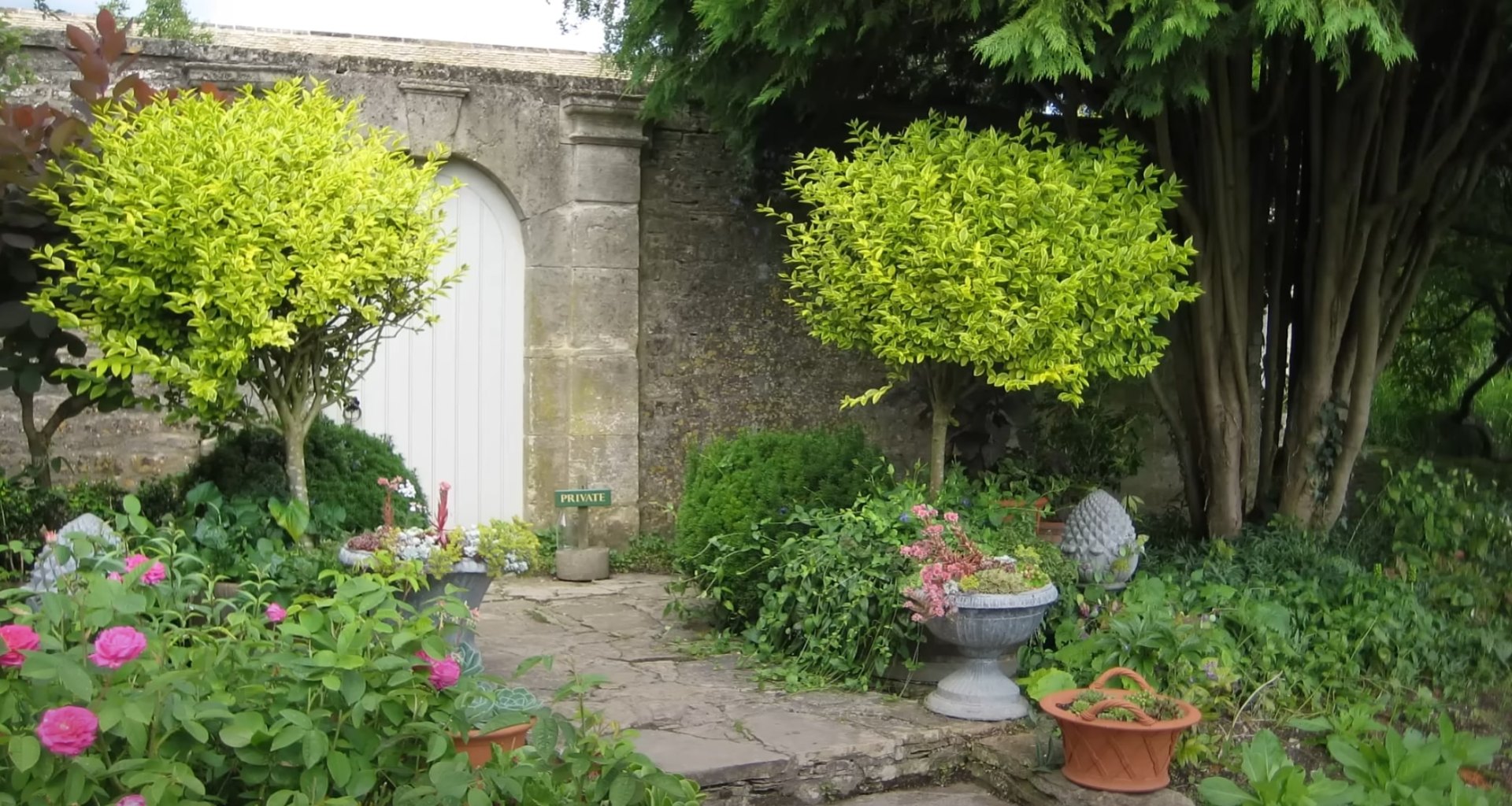 Traditional garden entrance design with stone archway and cottage garden plantings Private garden entrance with stone archway and cottage-style plantings in Channelview, TX