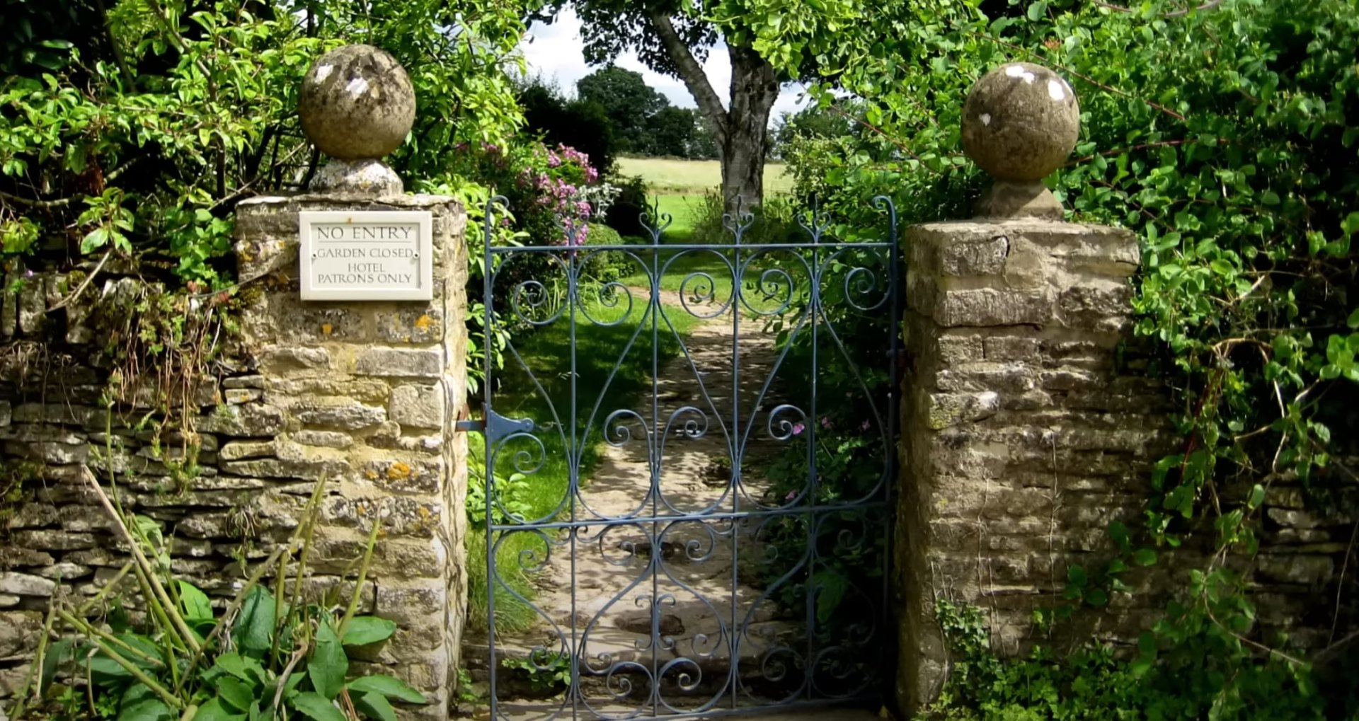 Classic landscape design featuring traditional stonework and mature garden plantings Traditional garden gate with stone pillars and mature landscaping in Channelview, TX